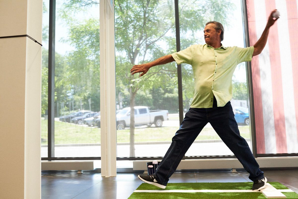 Adult man pitching a baseball at the Pitch! exhibition