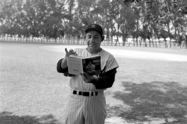 Yogi Berra in a field reading a book