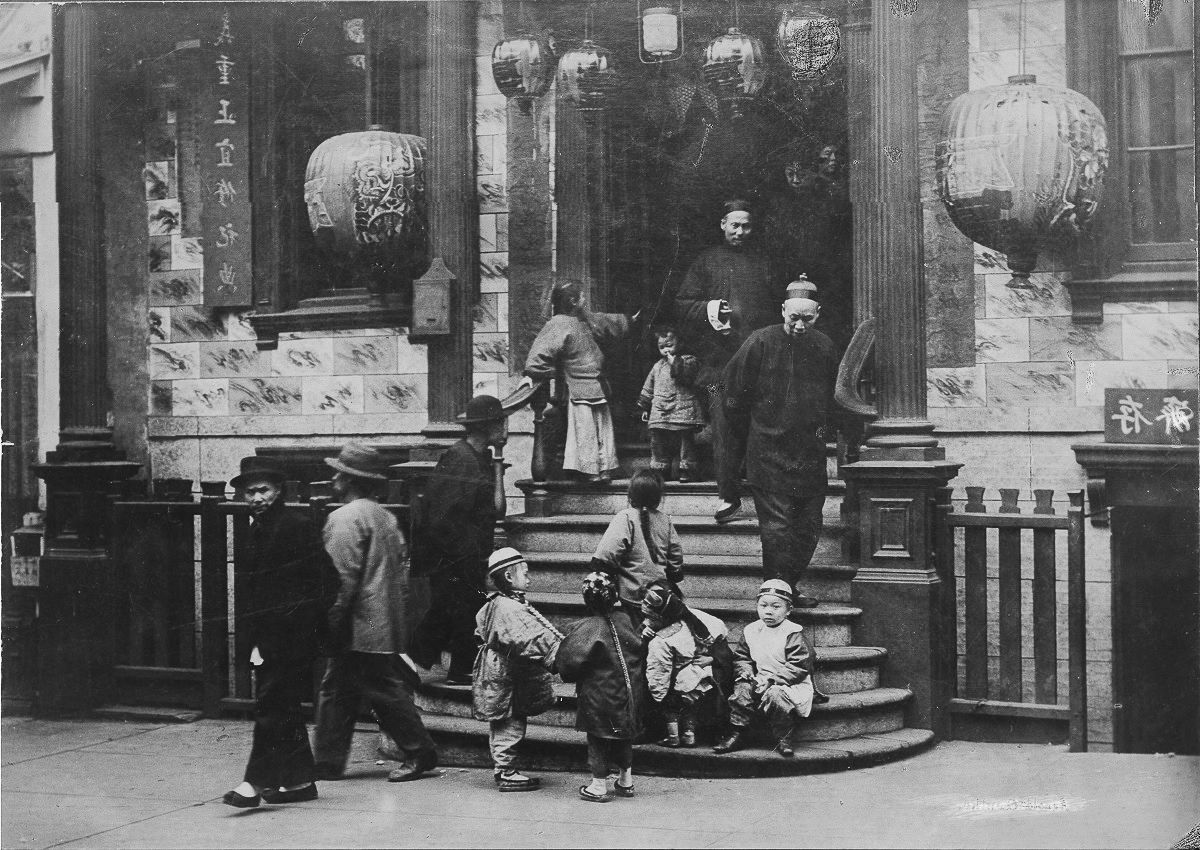 Black and white photo of a group of Chinese immigrants on a staircase with Chinese lanterns in the doorway