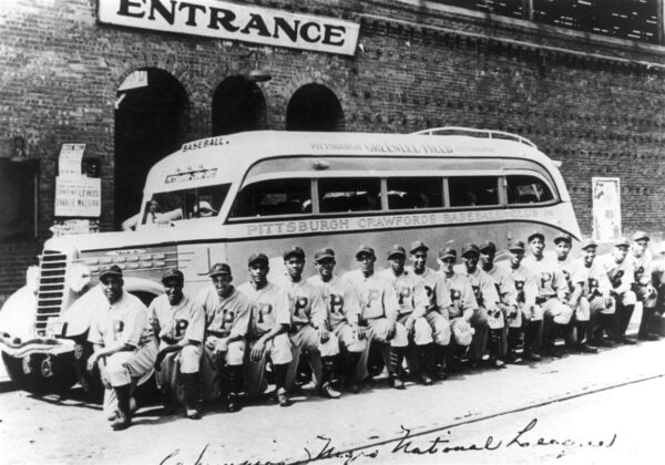 Baseball team lined up in front of a bus.