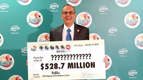 Photo of a lottery winner holding a $528.7 Million powerball poster