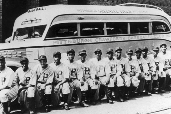 Baseball team lined up in front of a bus.