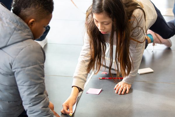 Children measuring stride with measuring tape in the museum.