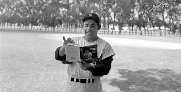 Yogi Berra in a field reading a book