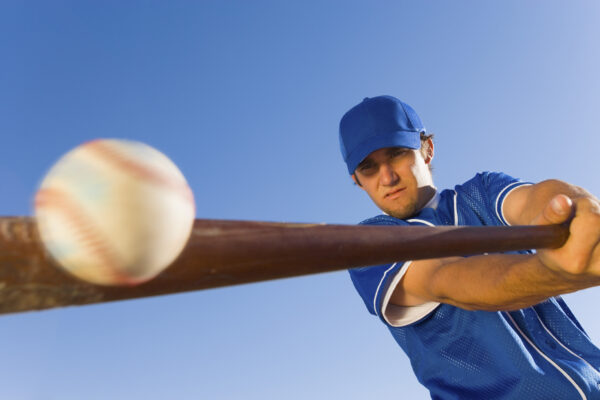 Male baseball player in blue uniform hitting a baseball