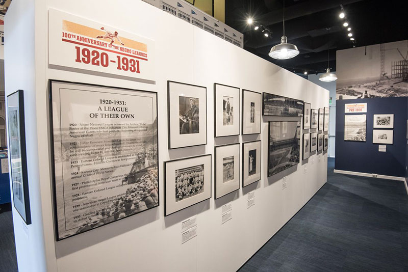 A wall of photos and information from 1920-1931 at the Discover Greatness exhibition