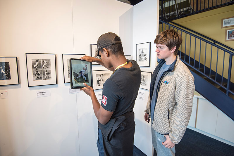 Two young men experiencing the augmented reality feature of the Discover Greatness exhibition