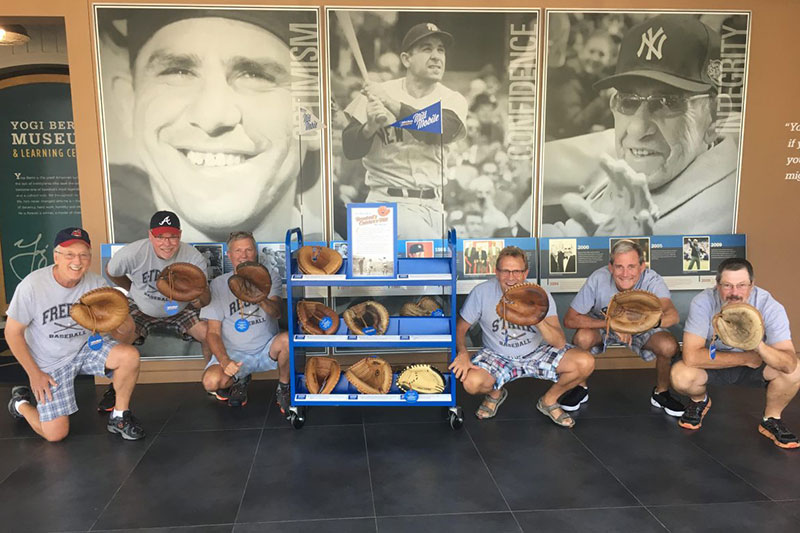 Adult men holding catcher's mitts around the Mitt Mobile