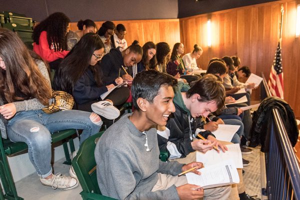 A large group of students participating in a writing activity in the seats of the Museum's auditorium