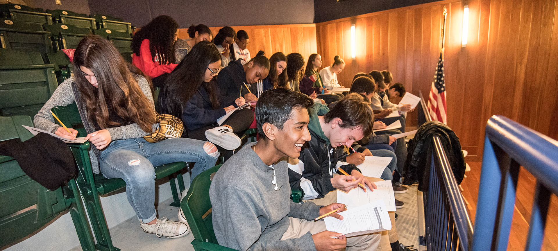 A large group of students participating in a writing activity in the seats of the Museum's auditorium