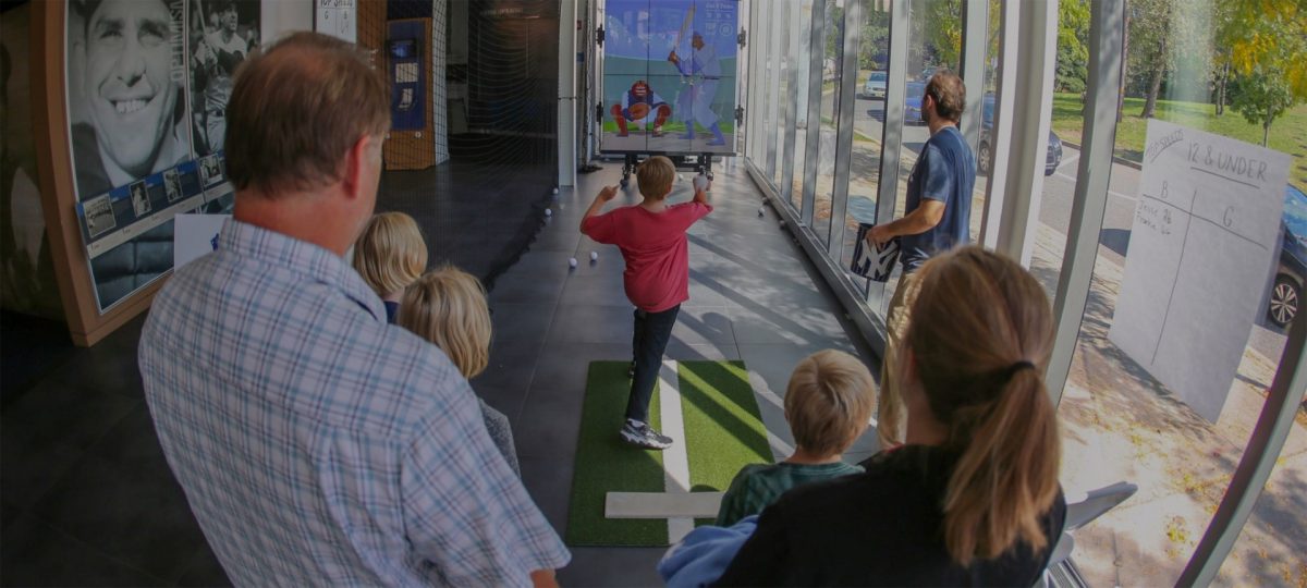 A boy throws a ball at a virtual pitching exhibit.